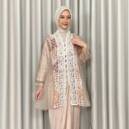 Woman wearing a beige lace kebaya by Kartinis Label and hijab against a neutral background