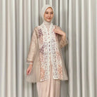 Woman wearing a beige lace kebaya by Kartinis Label and hijab against a neutral background
