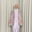 A woman wearing a traditional Kebaya Heather dress by Kartinis Label with batik and lace decorations, featuring a silhouette commonly associated with casual to elegant attire.