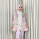 A woman wearing a lavender Kartinis Label Raline Kebaya, featuring batik patterns and lace embellishments.
