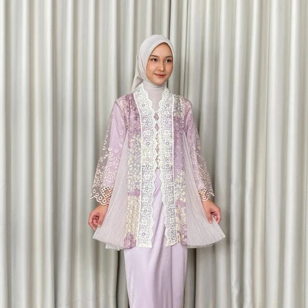 A woman wearing a lavender Kartinis Label Raline Kebaya, featuring batik patterns and lace embellishments.