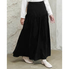Person wearing a black skirt by Mistyvori and white top against a concrete wall.