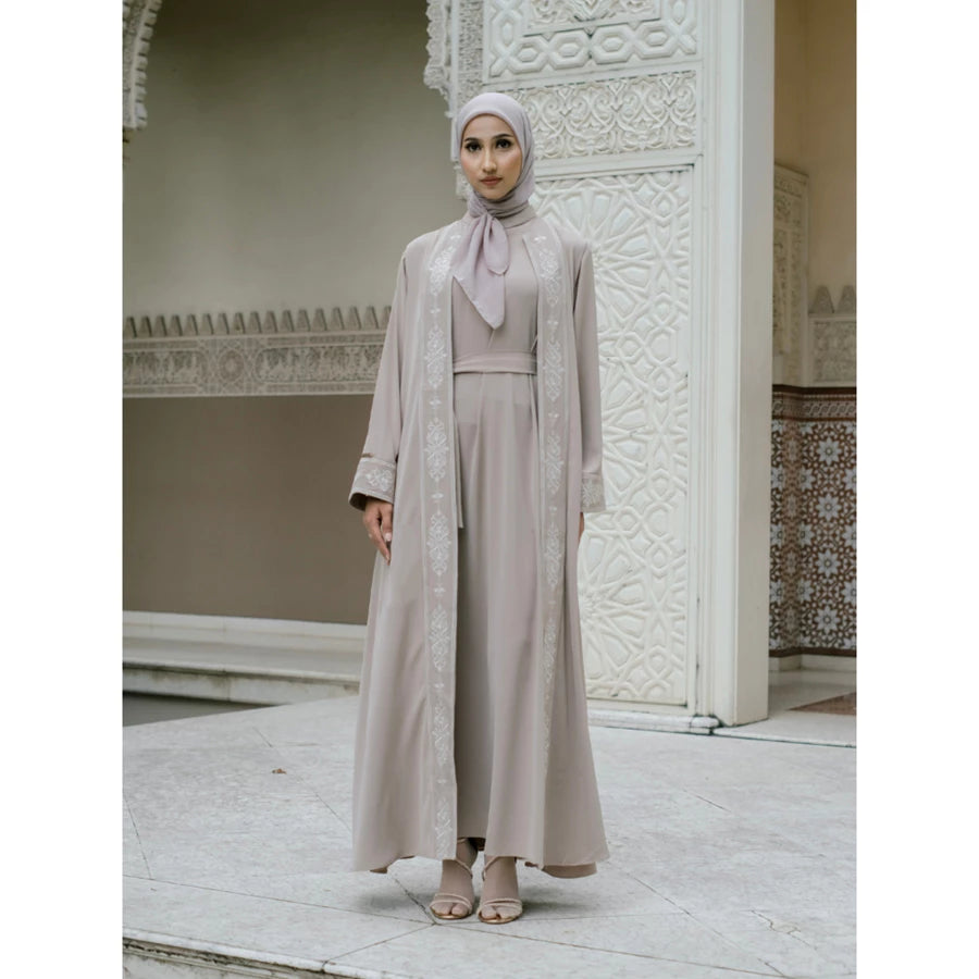 Woman in a beige abaya with white embroidery by Tubita.