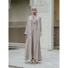 Woman in a beige abaya with white embroidery by Tubita.