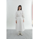 Person wearing a white top and patterned long white skirt by Yestoday on a gray background