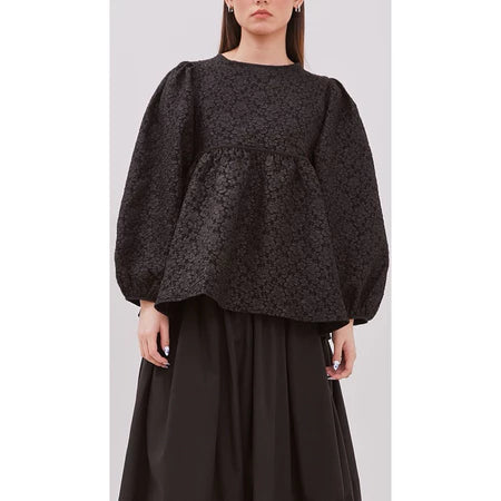 Person wearing a dark embossed peplum dress by Yestoday with puffed sleeves on a plain background