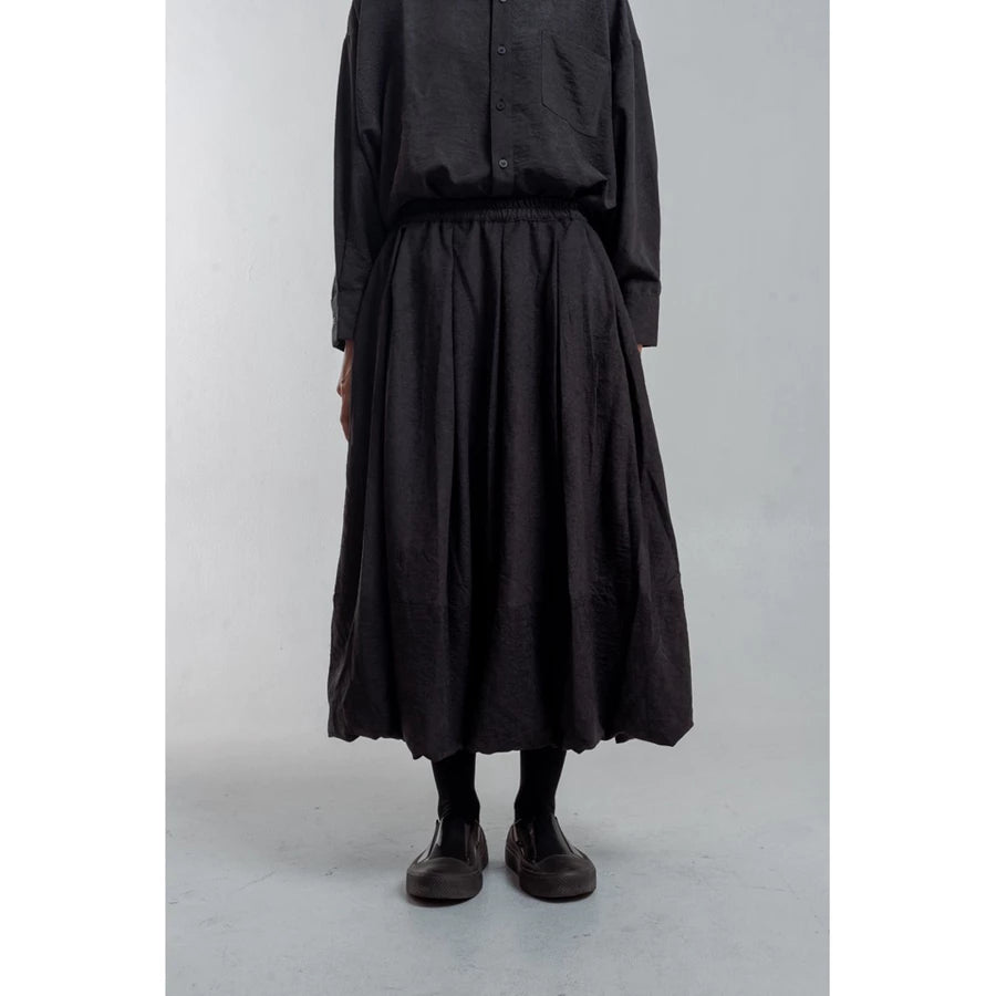 Person wearing a black outfit with a long skirt by Yestoday on a plain background
