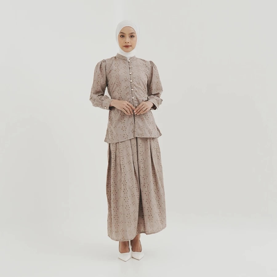 Woman wearing a patterned latte-colored blouse by Tunique on a white background
