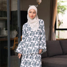 A woman wearing a white and blue floral ruffle top with long sleeves from BWBYAZ and a headscarf.