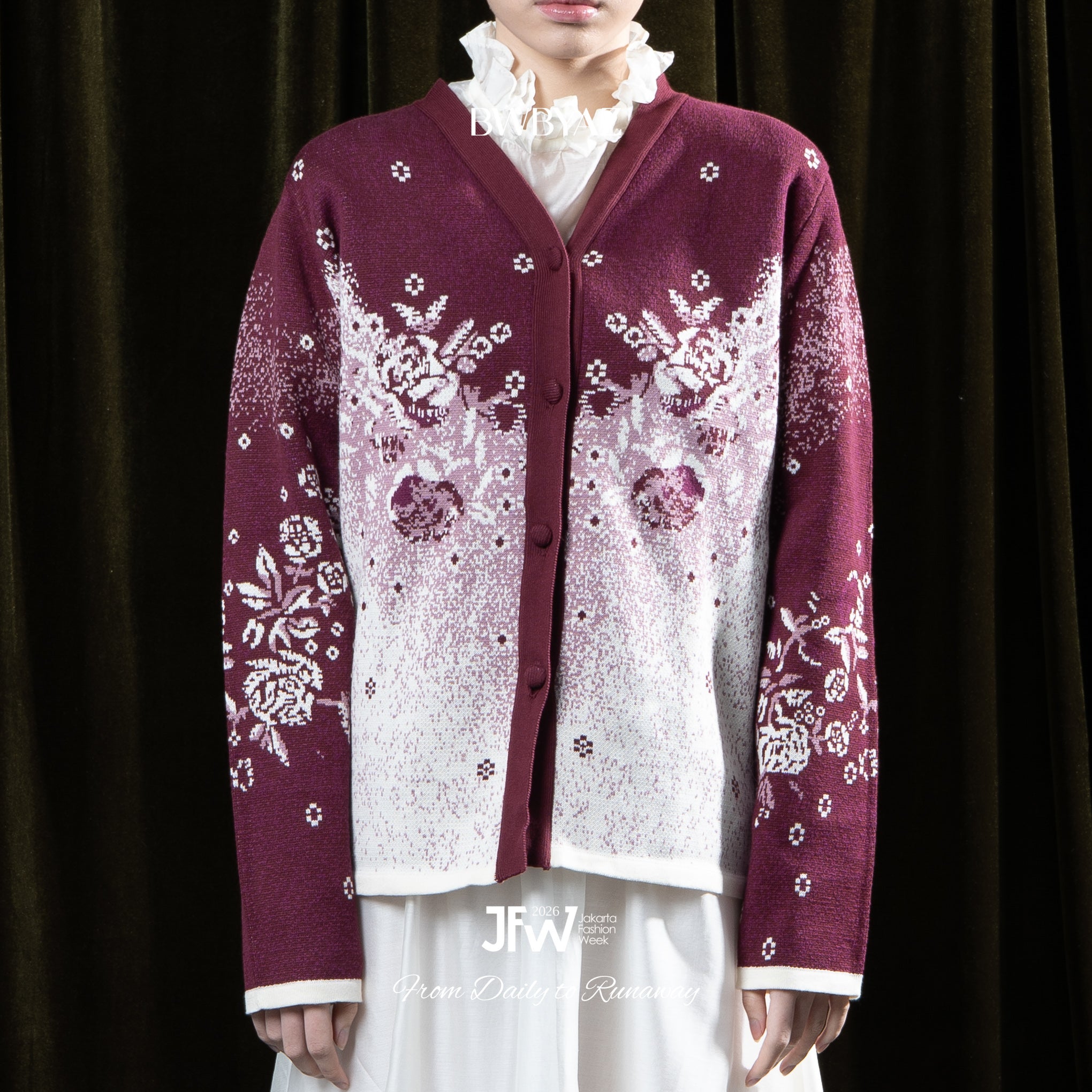 Person wearing a maroon cardigan with floral patterns by BWBYAZ on a dark background