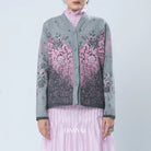 Person wearing a gray cardigan with pink floral patterns by BWBYAZ on a light blue background