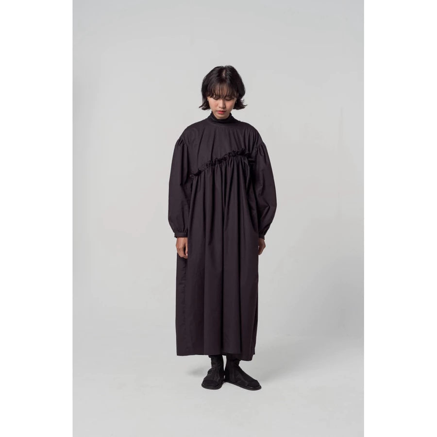 Person wearing a black ruffle dress by Yestoday against a plain background