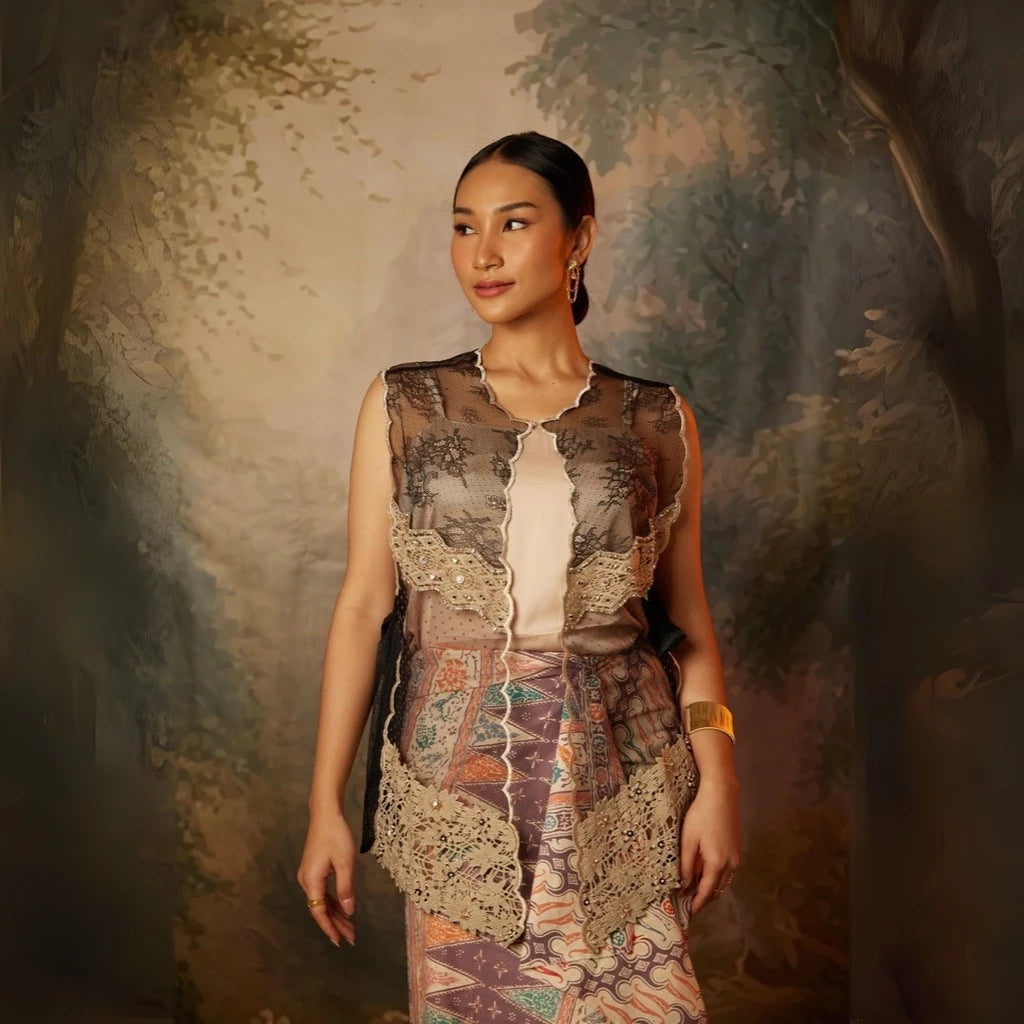 A woman wearing a traditional black kebaya vest by Kartinis Label with lace details and sequins.