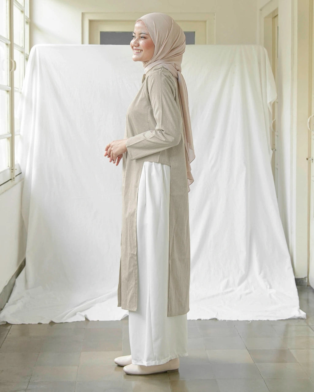 A woman wearing Mistyvori branded tunics in beige.

Seorang wanita memakai tunik berwarna beige dari brand Mistyvori.
