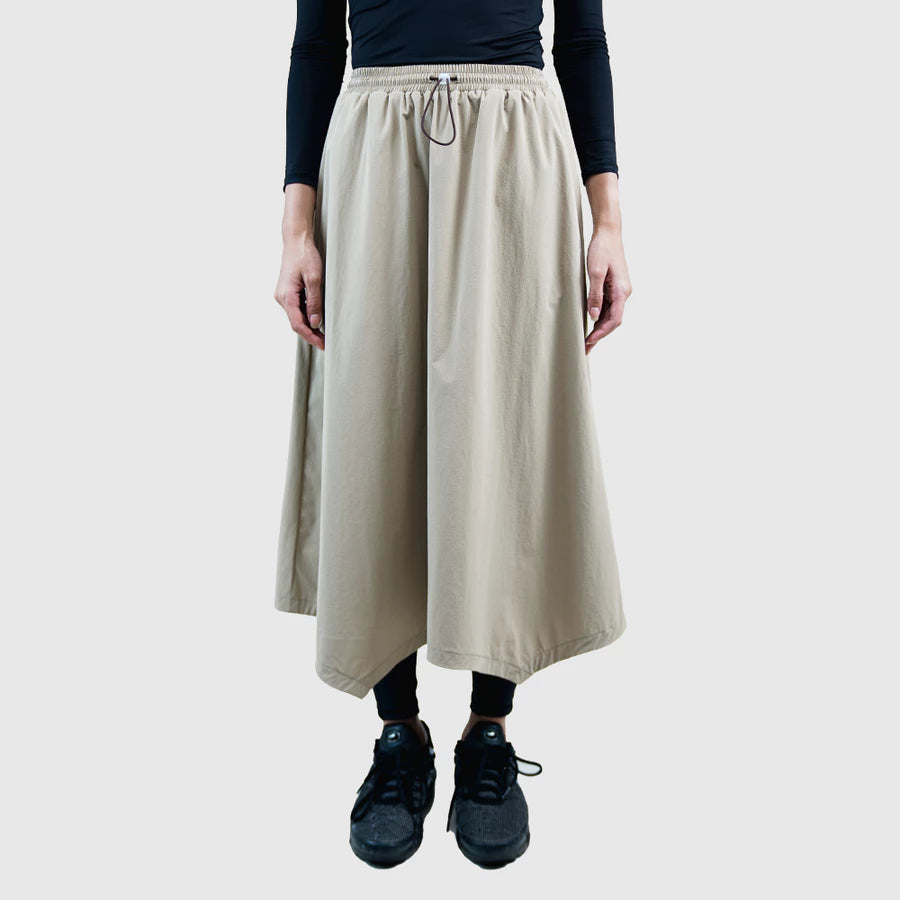 Person wearing a beige skirt by HIA with a plain background