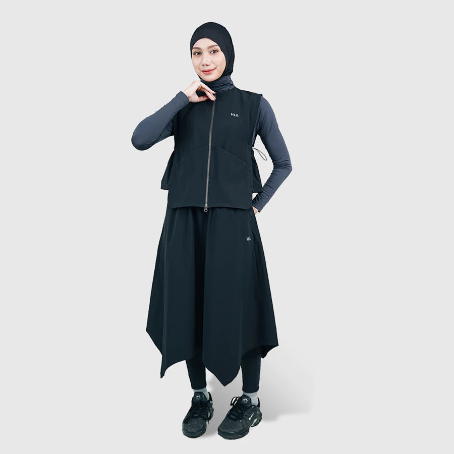 Woman wearing a black vest by HIA with a hijab on a white background