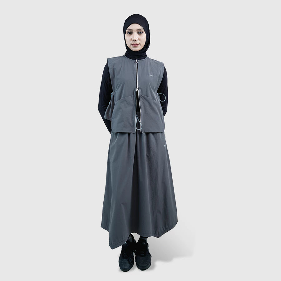 Person wearing a gray vest by HIA with a black hijab on a white background
