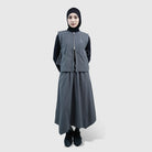 Person wearing a gray vest by HIA with a black hijab on a white background