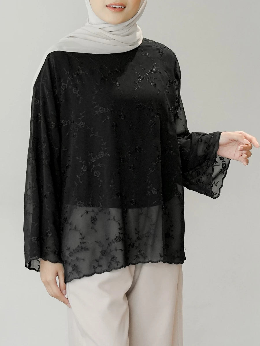 Woman wearing a black floral blouse by Mistyvori with white hijab on a gray background