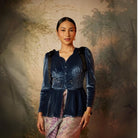 A woman wearing a long sleeve velvet top by Kartinis Label with pleated details and a fitted waist, in colors midnight blue.