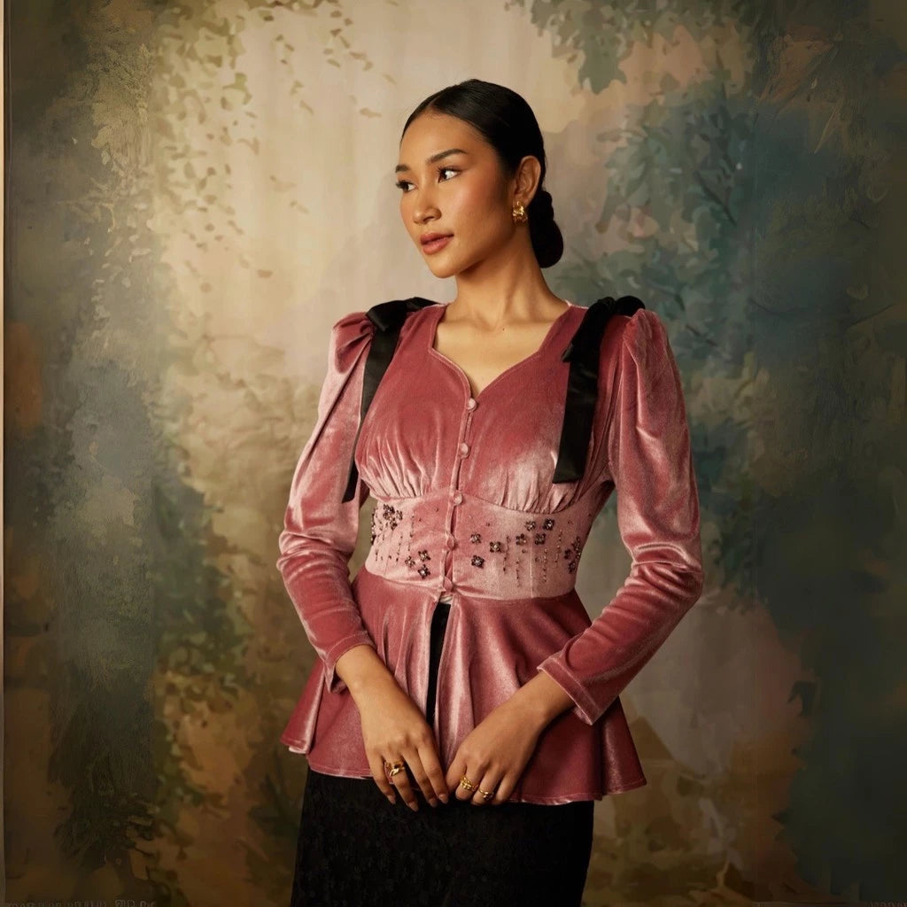 A woman wearing a long sleeve velvet top by Kartinis Label with pleated details and a fitted waist, in colors mauve.