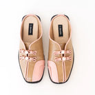 Pair of tan and pink mules flats by Dianable with decorative bows on a white background