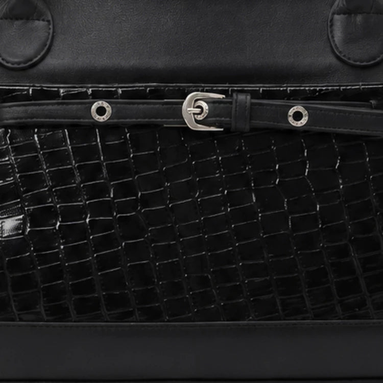 Close-up of a black textured leather handbag by Cekhas with a silver buckle.