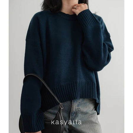 Person wearing a dark blue oversized sweater with a plain background, featuring the brand 'kasyalia'.