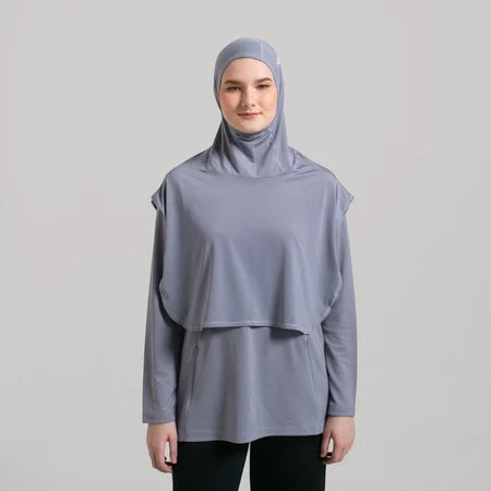 Person wearing a gray sport hijab by Noore and matching long-sleeve top on a light gray background