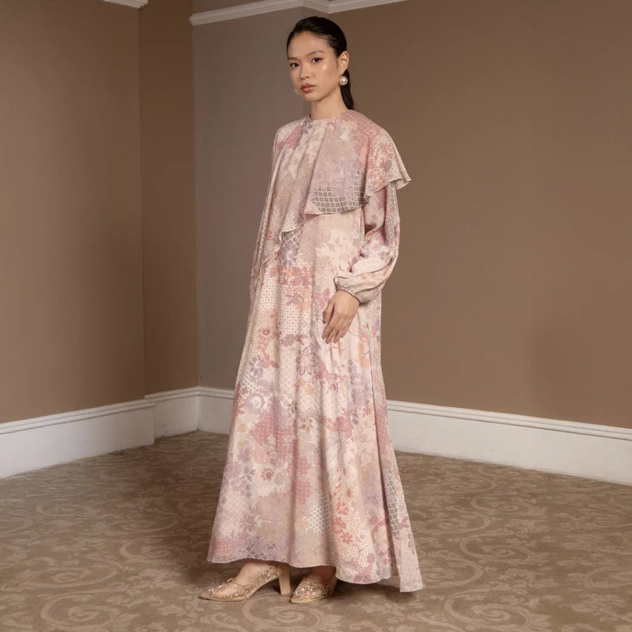 Woman wearing a peach-colored floral dress by Hijabchic and shawl in a room with beige walls and carpet.