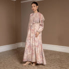 Woman wearing a peach-colored floral dress by Hijabchic and shawl in a room with beige walls and carpet.