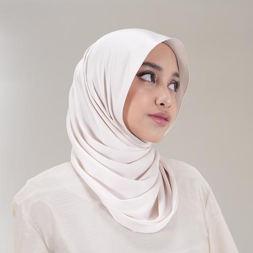 Woman wearing a light pink pashmina hijab by Tantri Namirah Official against a plain background