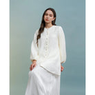 Woman wearing a white blouse by Kasa Heritage against a light blue background