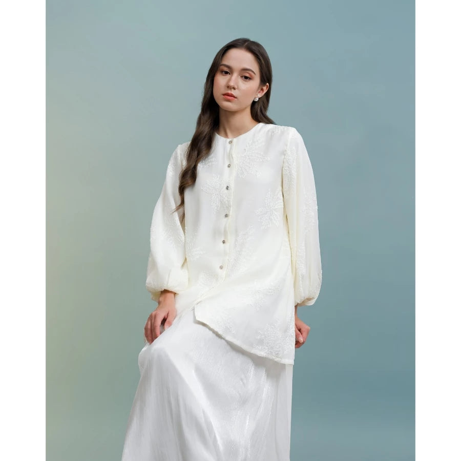 Woman wearing a white blouse by Kasa Heritage against a light blue background