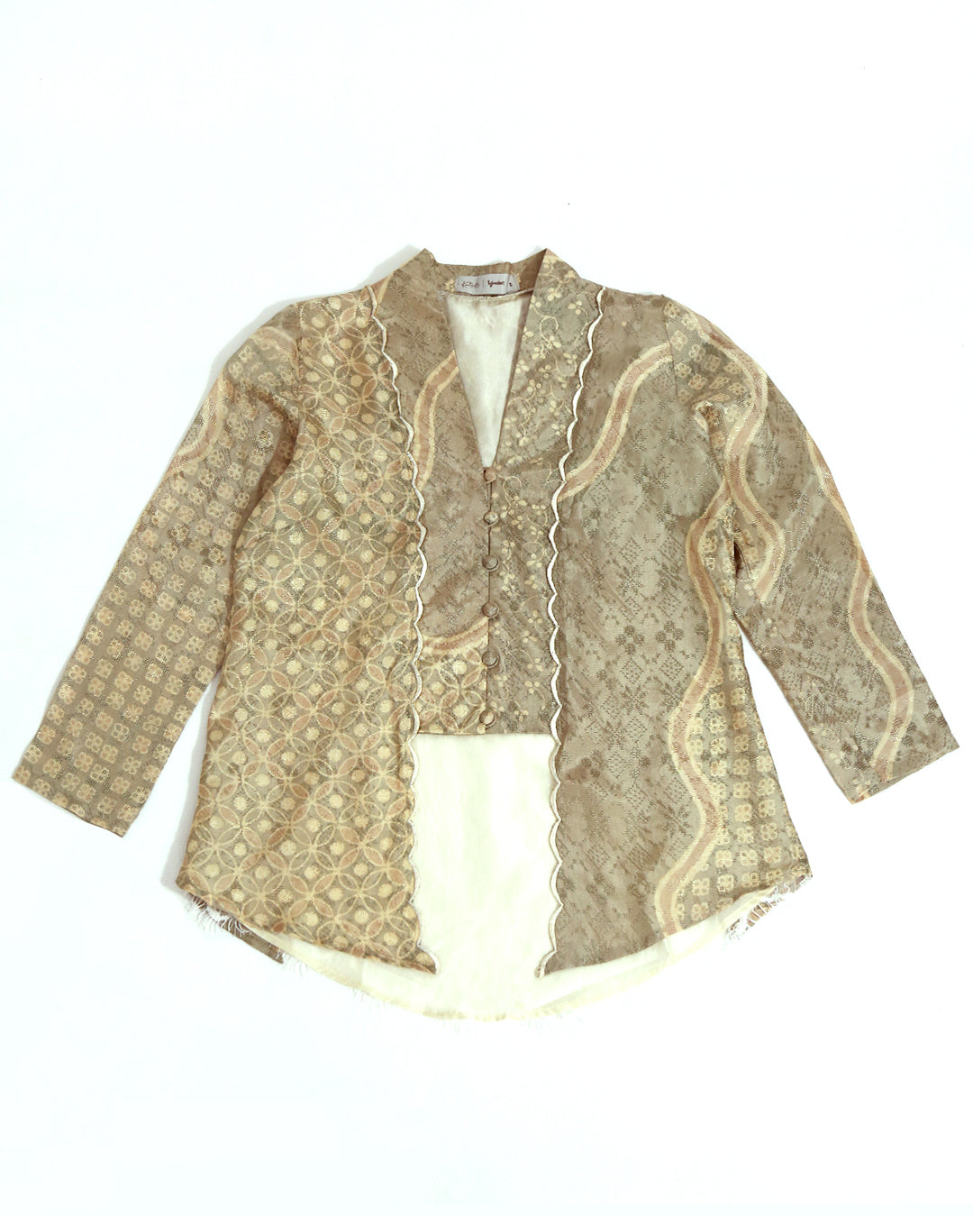 A traditional long sleeve Kutubaru kebaya blouse by Kartinis Label with beige and white batik patterns and embroidery details on the front.
