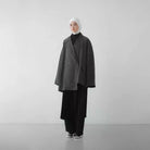Person wearing a dark gray oversized blazer by Rashawl and black pants on a white background