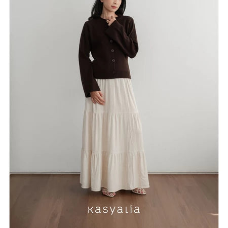 Person wearing a brown top and white skirt with 'kasyalia' branding.