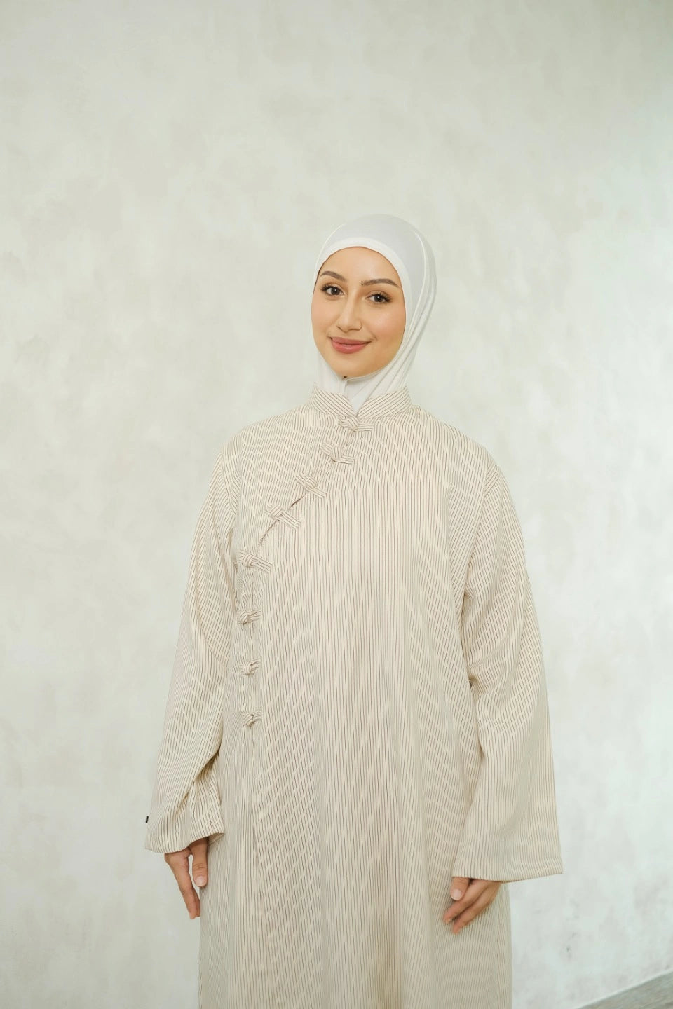 Woman wearing a white hijab and ivory-colored tunic by Tufine against a white background

Seorang wanita yang mengenakan hijab putih dan tunik berwarna krem dari Tufine dengan latar belakang putih