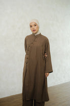 Woman wearing a brown long-sleeve tunic by Tufine and pants with a beige hijab against a white wall.

Seorang wanita mengenakan tunik lengan panjang berwarna cokelat dari Tufine dan celana panjang, serta hijab berwarna krem, dengan latar belakang dinding putih.