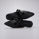 A pair of black pointed-toe mule sandals by Cekhas with double buckle straps, shown from a top-down angle on a light gray background.