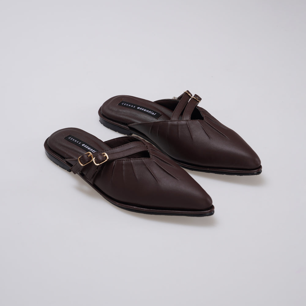 A pair of dark brown leather pointed-toe mule sandals by Cekhas with gold-tone buckle straps, shown on a light gray studio background.