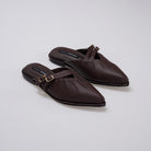 A pair of dark brown leather pointed-toe mule sandals by Cekhas with gold-tone buckle straps, shown on a light gray studio background.
