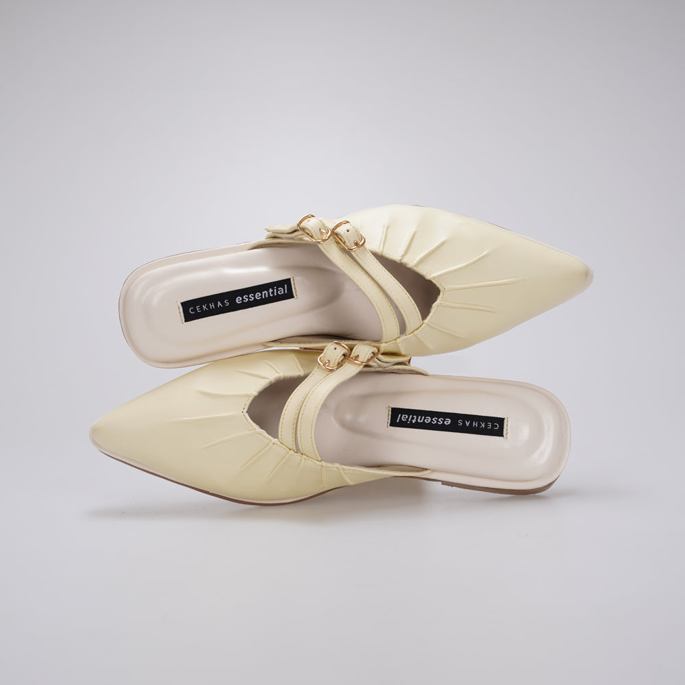 A pair of butter yellow-colored pointed-toe mule sandals by Cekhas with gold-tone hardware and a strap detail, shown from a top-down view on a light gray background.