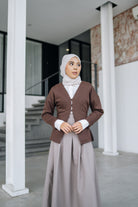 A woman wearing a fitted cardigan in a coffee color by Swifter, paired with a hijab, standing indoors.