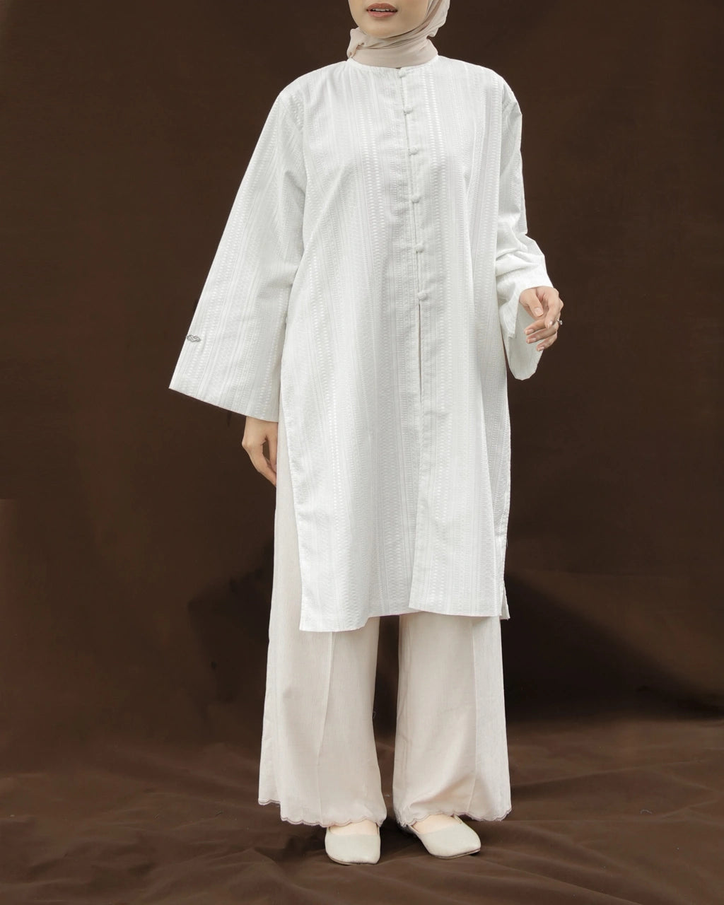 Woman wearing a white tunic by Mistyvori and a ivory pants on a brown background.

Seorang wanita mengenakan tunik putih dari Mistyvori dan celana panjang berwarna gading dengan latar belakang cokelat.
