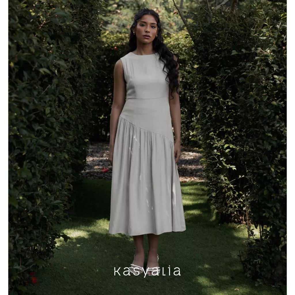 Woman in a white dress standing in a garden with 'kasyalia' branding.