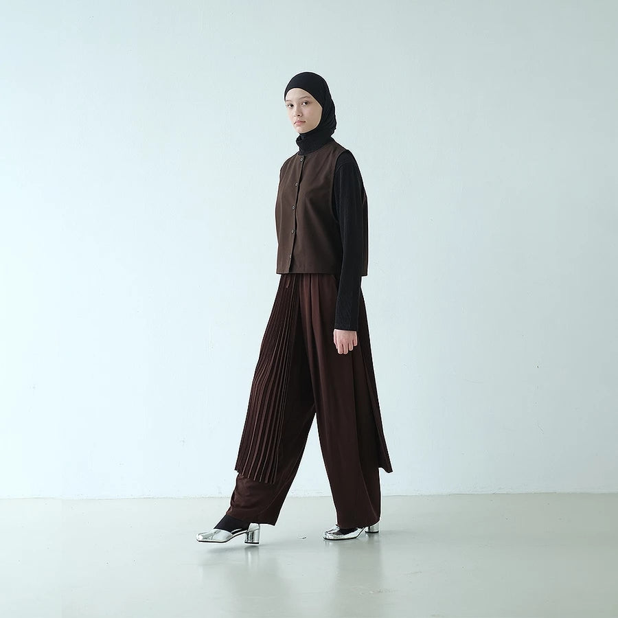 Person wearing a brown top and barrel pants by Rashawl with a black hijab on a white background