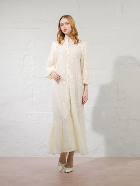 Woman wearing a long, light ivory-colored dress by Kasa Heritage against a white background