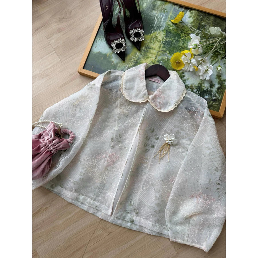 Soft pink lace outer by Haidee Orlin on a wooden surface with a decorative tray and shoes in the background.