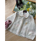 Soft pink lace outer by Haidee Orlin on a wooden surface with a decorative tray and shoes in the background.